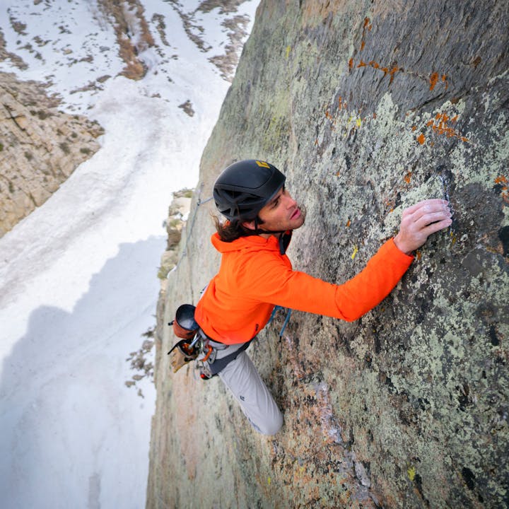 A climber in a Coefficient Storm Hoody inspects a granite crimp. 