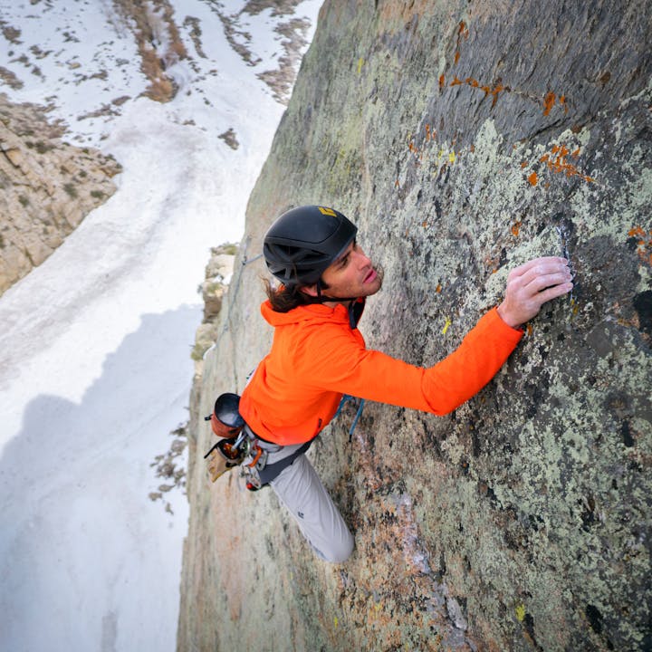 A climber in a Coefficient Storm Hoody inspects a granite crimp. 