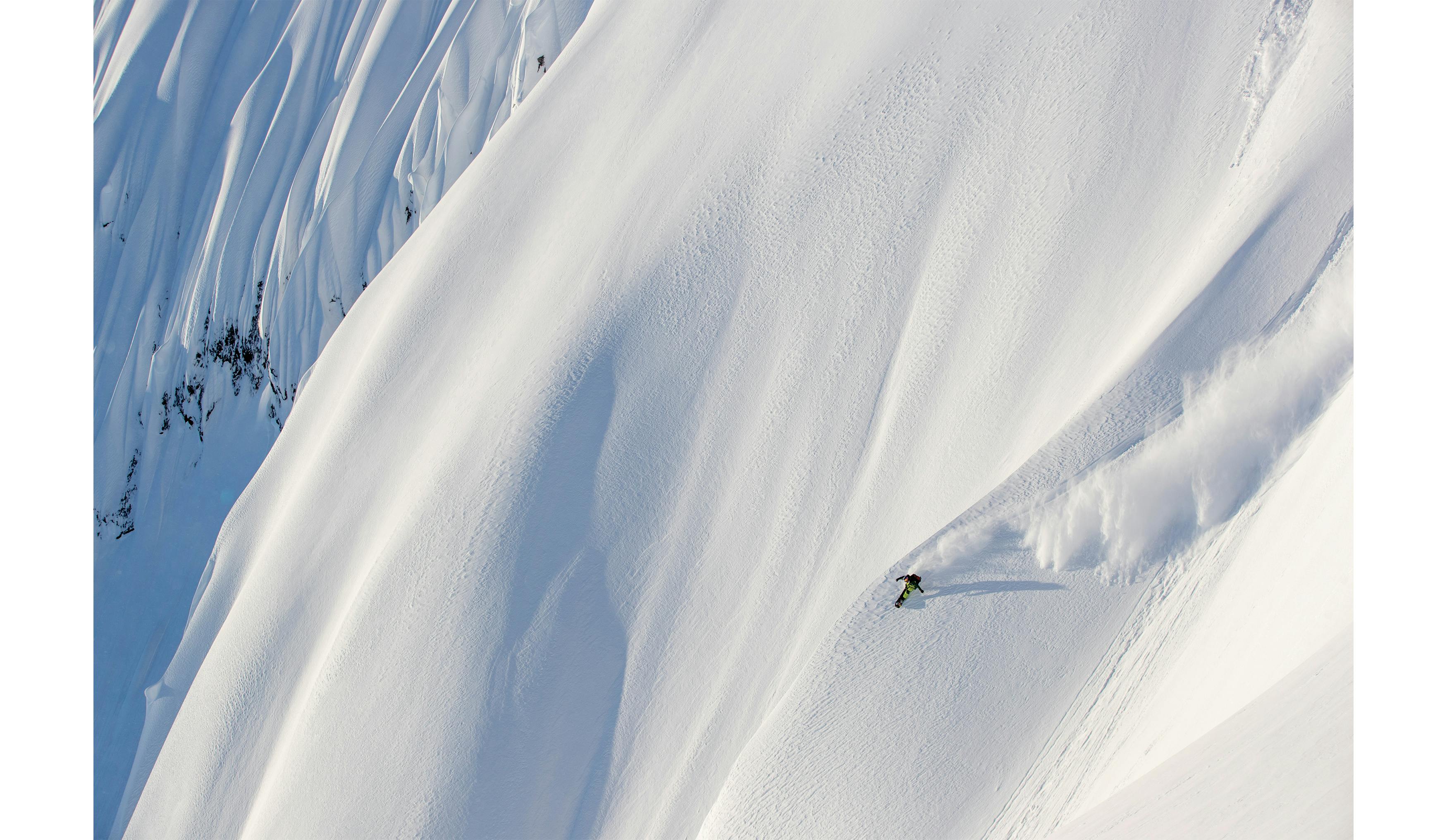 Black Diamond athlete John Jackson Snowboarding down a big mountain line in Alaska. 