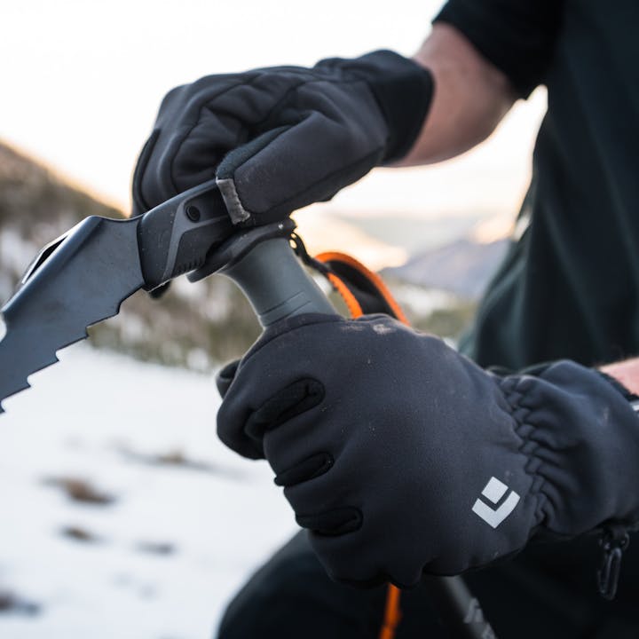 A skier in Heavyweight Screentap Gloves adjust a Whippet attachment. 