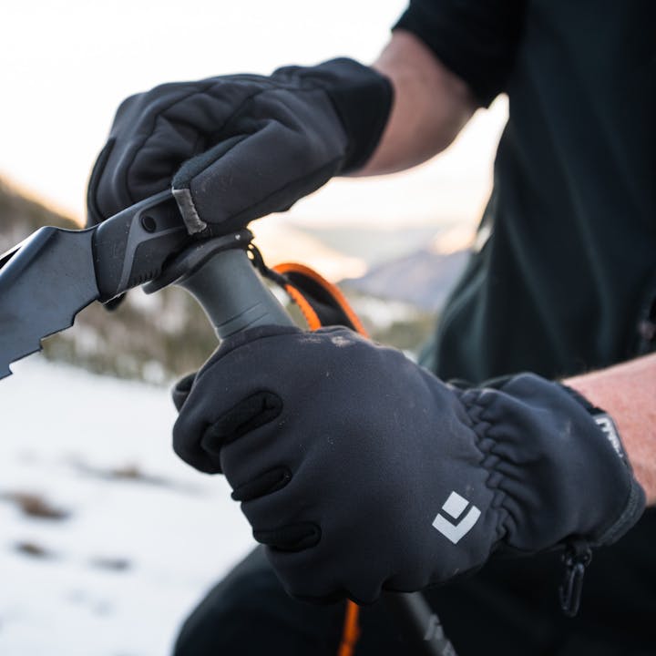 A skier in Heavyweight Screentap Gloves adjust a Whippet attachment. 