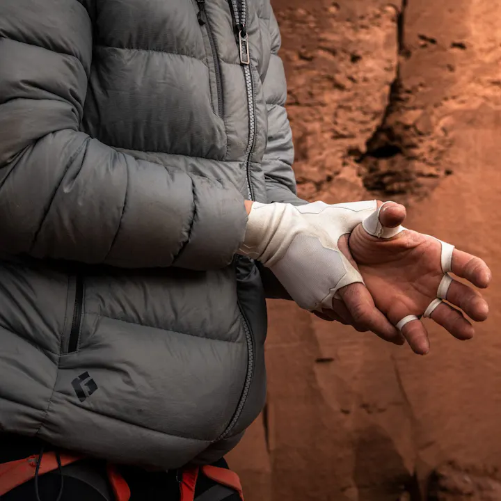 Photograph by Andy Earl of woman putting on crack gloves in the desert | Climbing Gloves