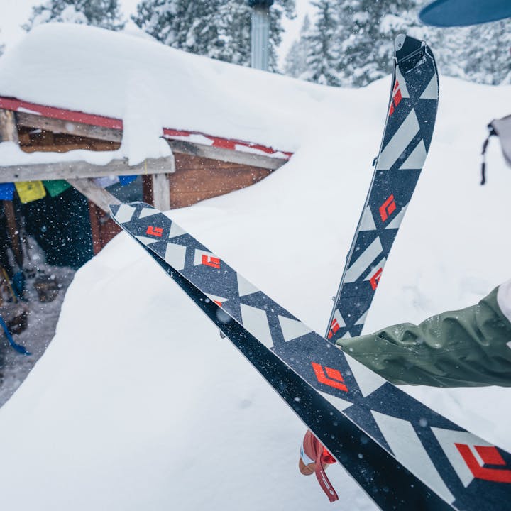 A splitboarder puts on her Black Diamond skins outside a yurt as the snow falls.