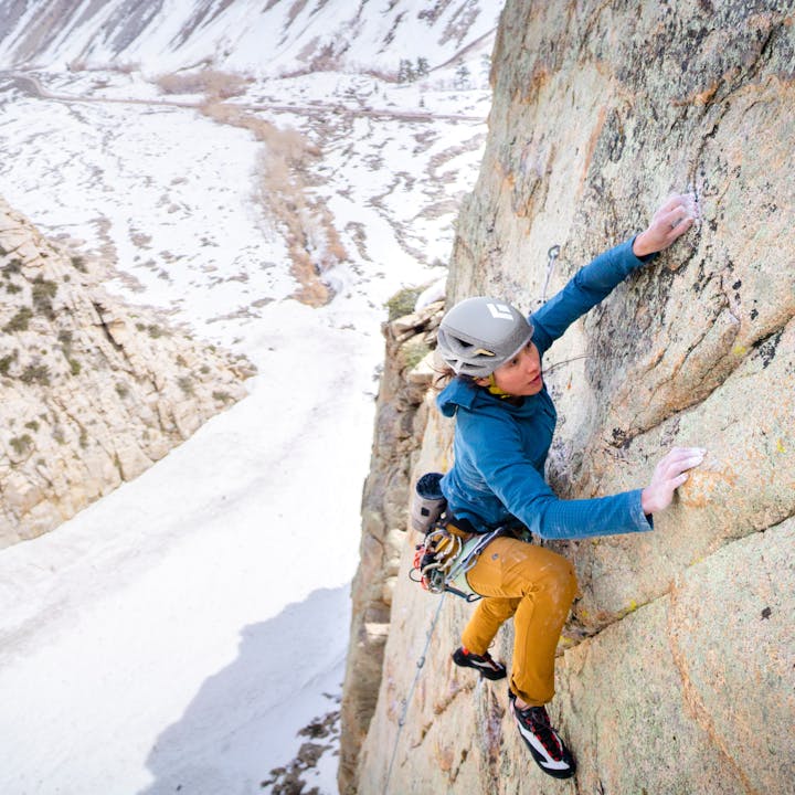 A climber in a Vapor Helmet and Coefficient Storm Hoody reaches for a granite hold. 