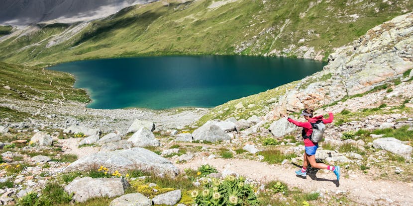 Kim Strom running by an alpine lake with Black Diamond Distance series pack. 