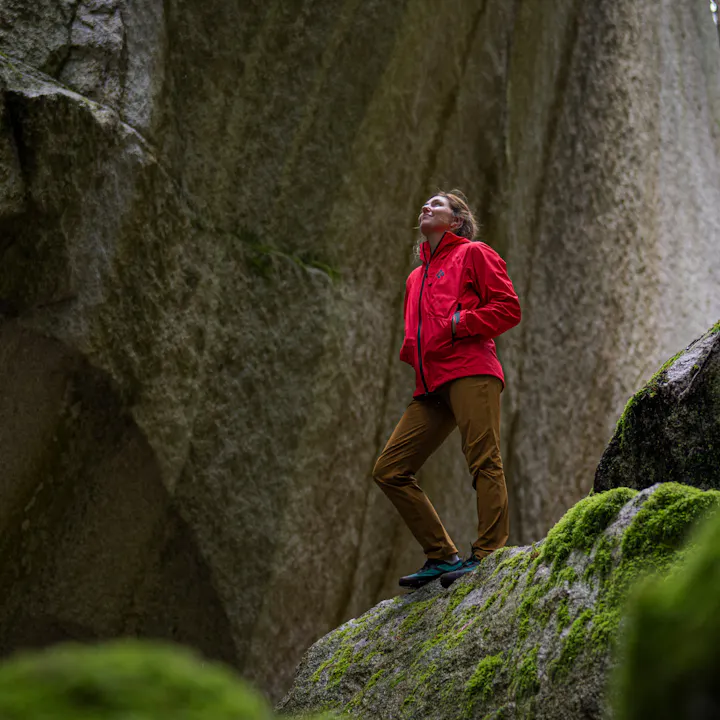 A hiker in a Black Diamond Shell looks up at looming granite walls.