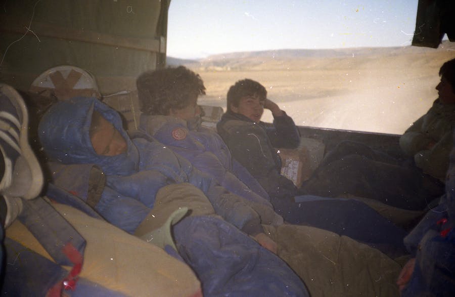 Three teens sitting in the back of an army truck