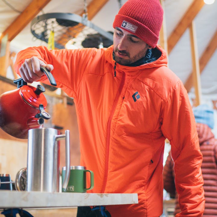 A backcountry skier makes coffee in a yurt. 