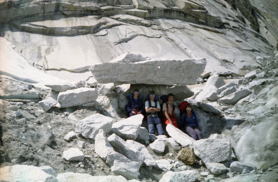 Four teenagers sit under a large rock