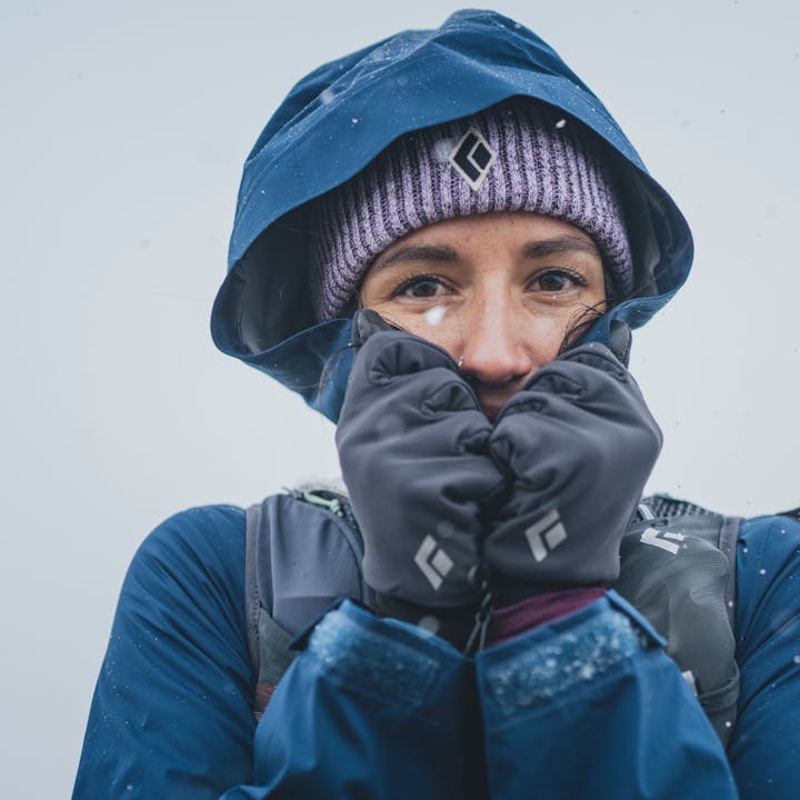 A hiker bundles up in her Black Diamond Stormline Stretch Rain Shell as it begins to snow. 