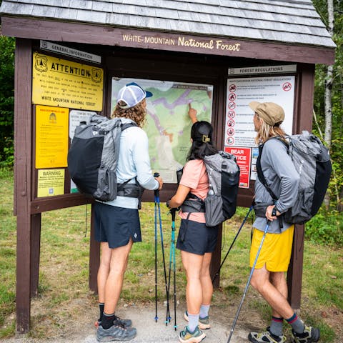Three hikers in Beta Light Packs plan a trip in the White Mountains. 