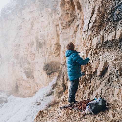 A climber wears the Vision Down Parka to belay their partner on a cold day at the crag. 