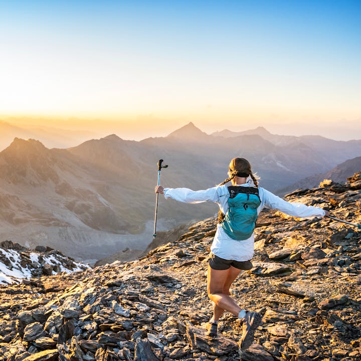 A trail runner in a Distance Pack up on a ridge at sunset. 