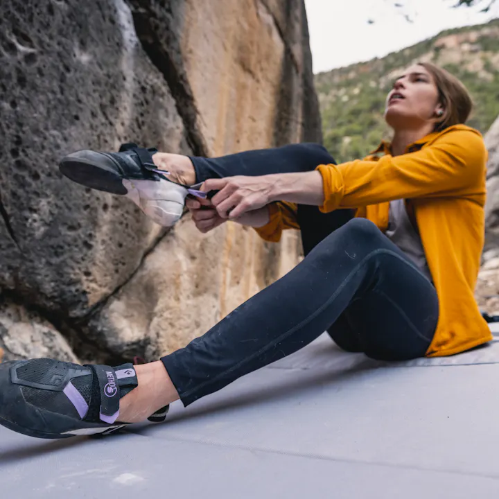 A climber in Session Tights pulls on her Method S Climbing Shoes before hopping on a boulder problem. 