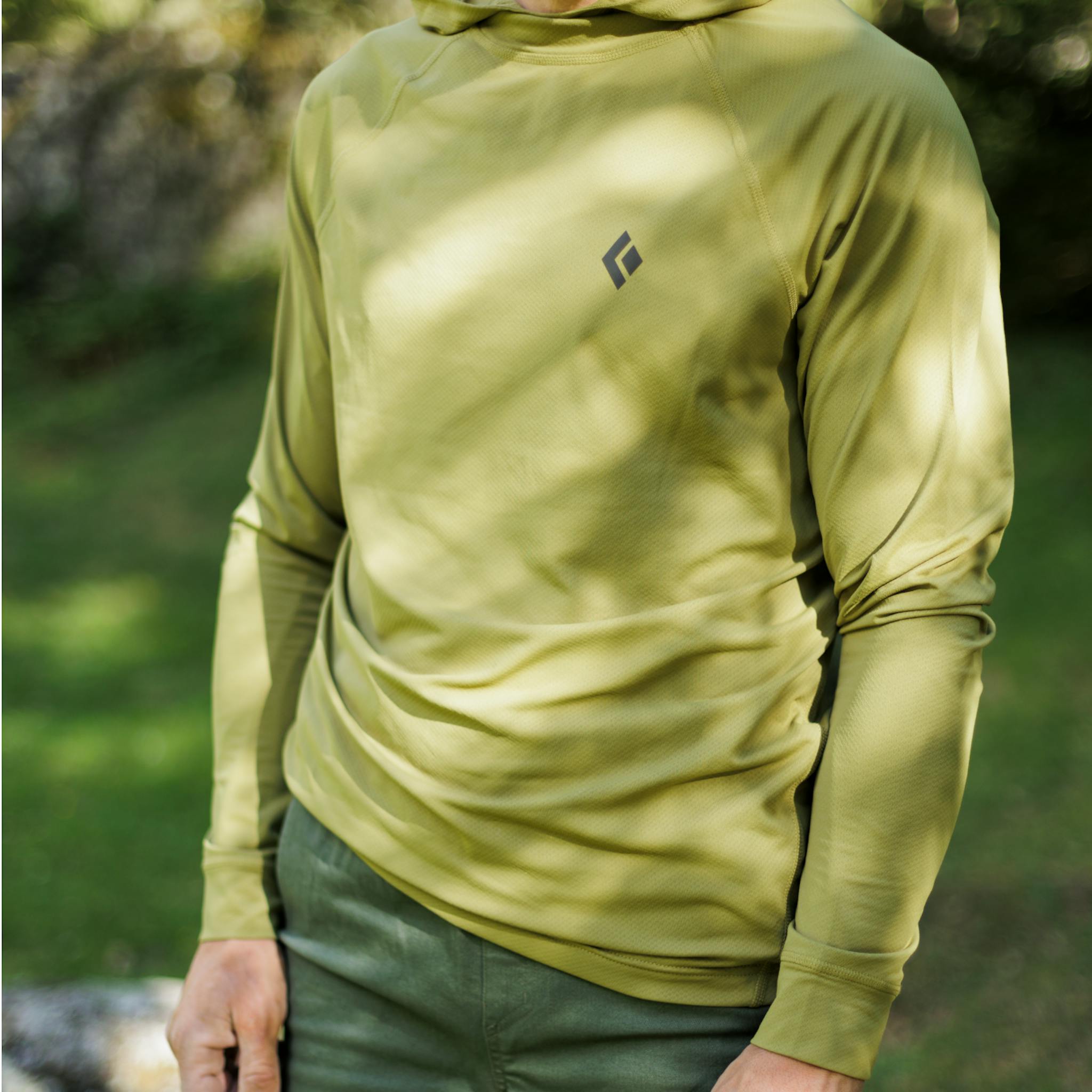 A boulderer stands in his green Alpenglow Hoody.