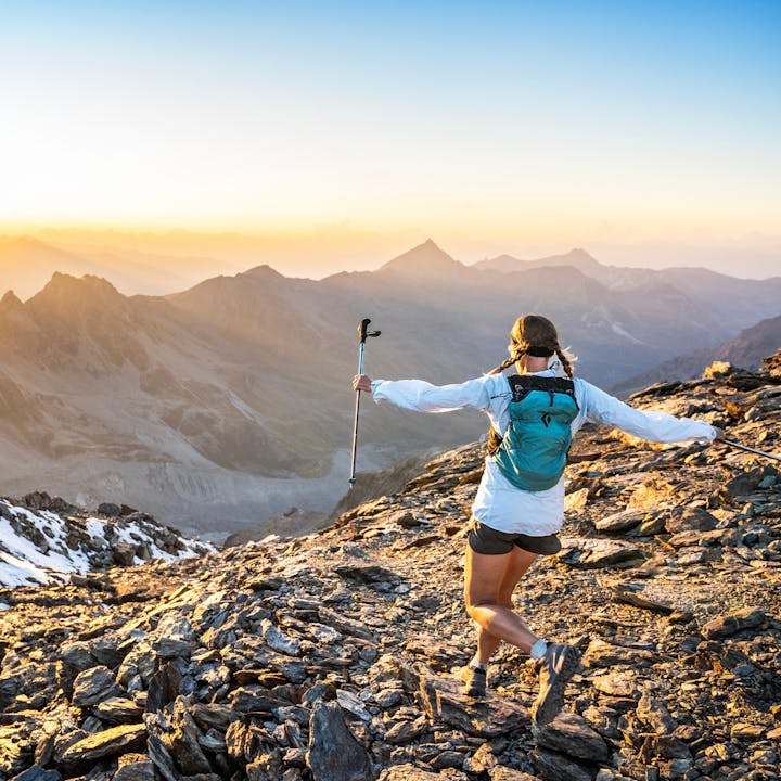 A runner jumps down a scree field at dusk in a Black Diamond Distance Pack.