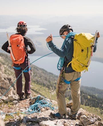 A climber coils a rope wearing the Speed 50 backpack. 