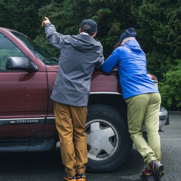 Two climbers in Black Diamond jackets plan their route in the parking lot before a day of climbing. 
