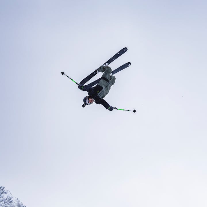 A backcountry skier does a back flip wearing the Recon Stretch Pro Shell and Bibs. 
