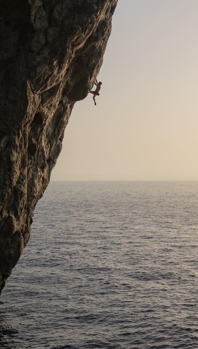 Climber climbing, ocean in background