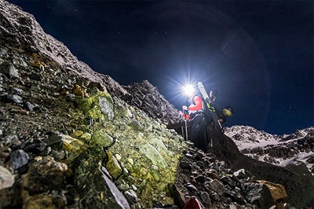 Photo of Antte Lauhamaa hiking up a mountain with a headlamp on.