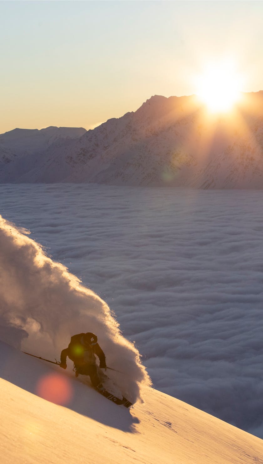 Dawn patrol skier descending the mountain as the sun rises.