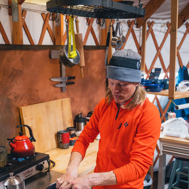BD athlete Bjorn Leines in a Black Diamond Coefficient Fleece washes dishes after a day or skiing. 