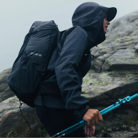 A hikers pushes on through the rain with their waterproof Beta Light Series Backpack. 
