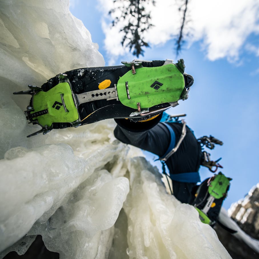 A climber sticks his crampons deep into some vertical ice.