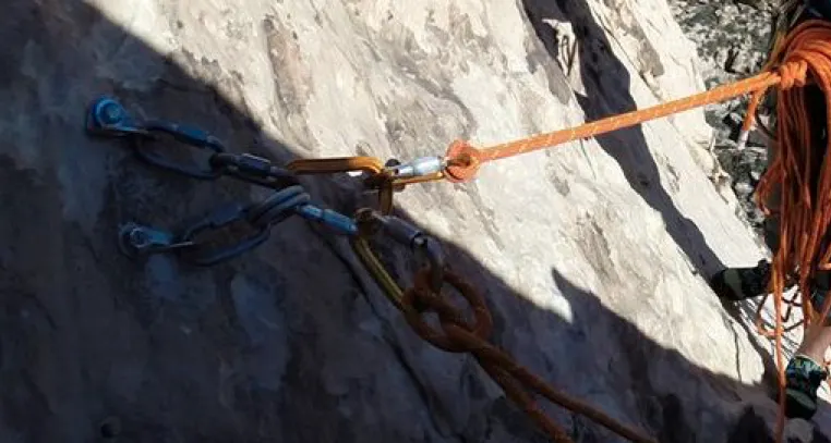 Carabiners attached to anchors and ropes on a wall