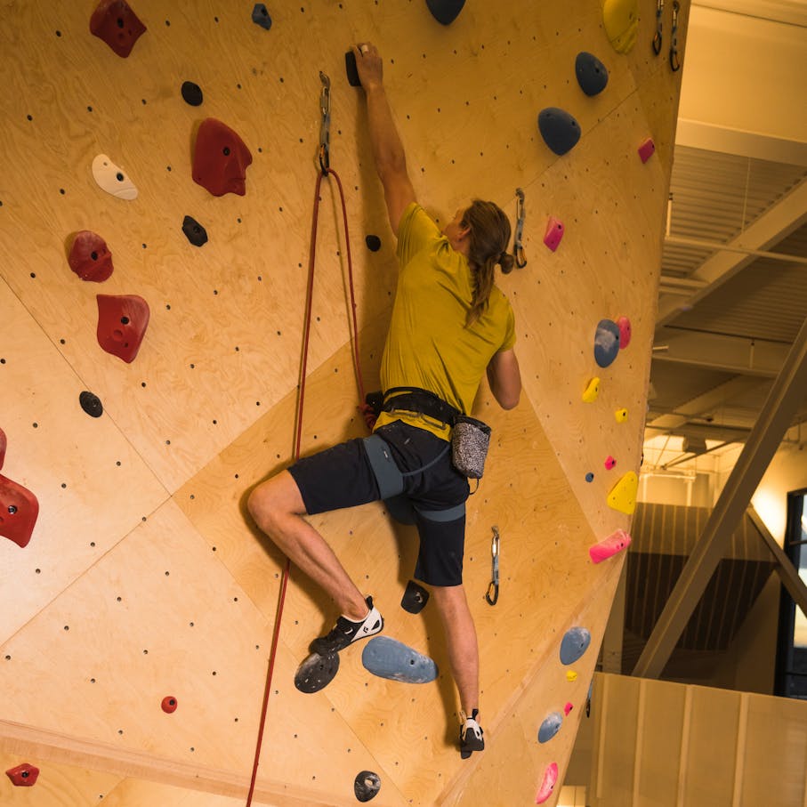A climber on a gym wall in momentum climbing shoes