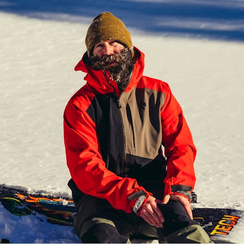 BD Athlete Eric Jackson sitting on his snowboard. 