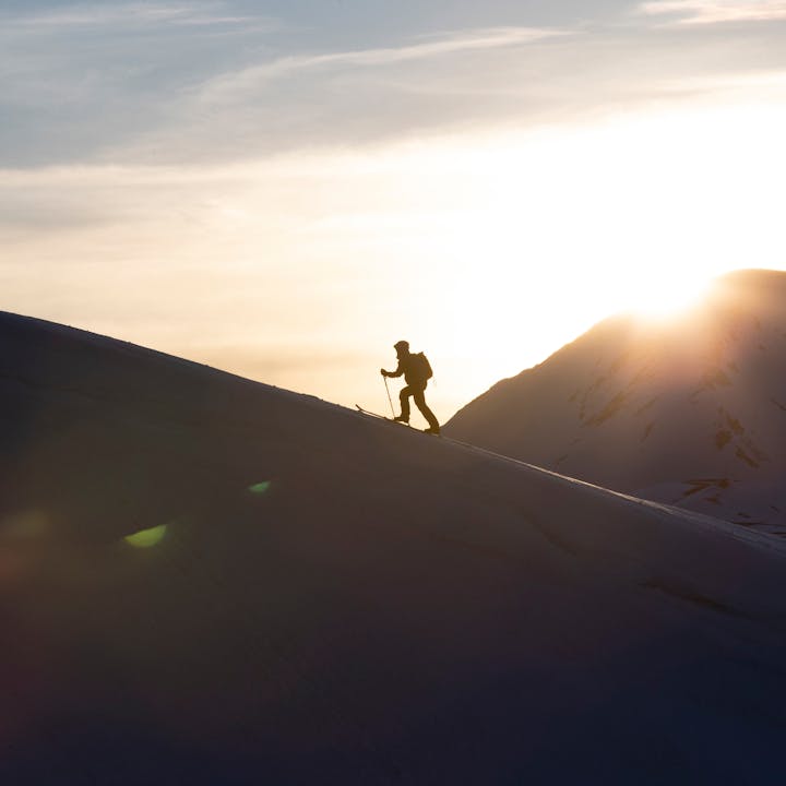 Skier skinning up a mountain ridge line. 