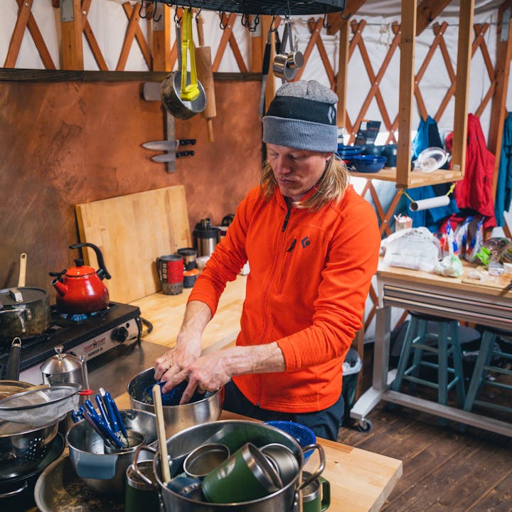 BD athlete Bjorn Leines in a Black Diamond Coefficient Fleece washes dishes after a day or skiing. 