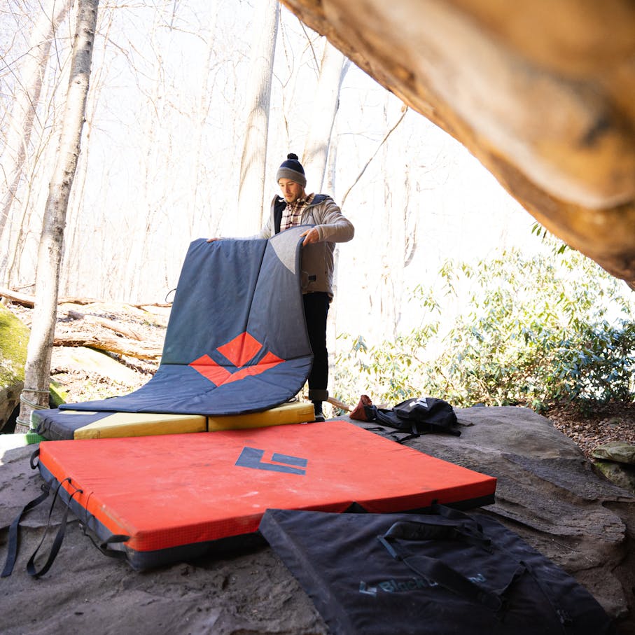 A climber sets up a gap stopper bouldering pad.