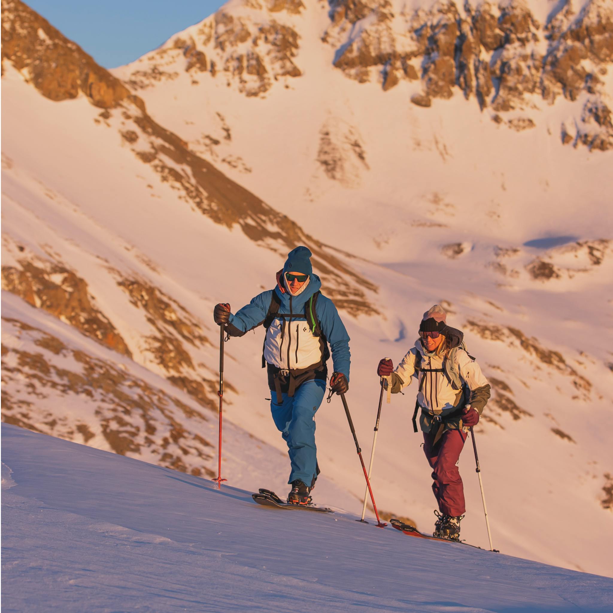 Zwei Skitourengeher, die in der Morgendämmerung auf Skitour gehen.