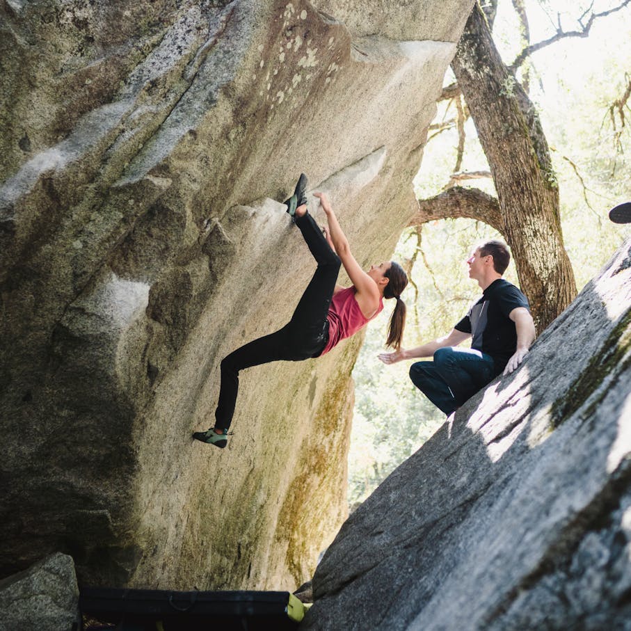 Une grimpeuse tente un problème de rocher en portant le pantalon en denim forgé pour femmes.
