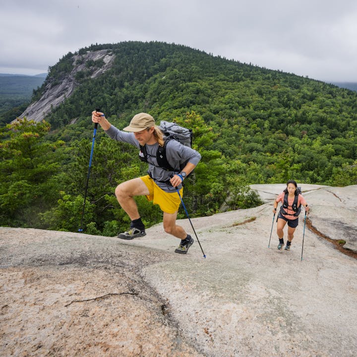 Two hikers use Distance Poles to walk across a granite dome. 