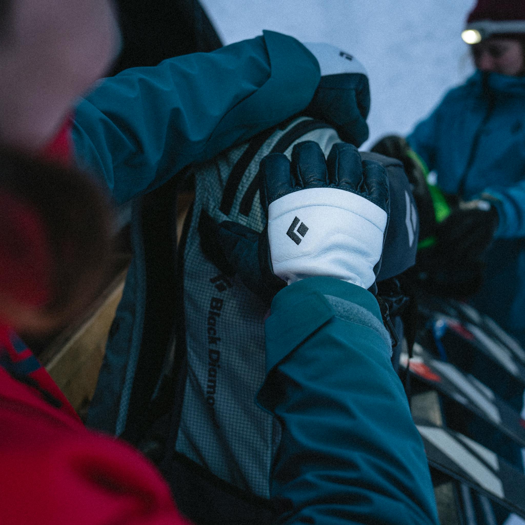 A skier in Women's Spark Gloves zips up her pack before a tour.