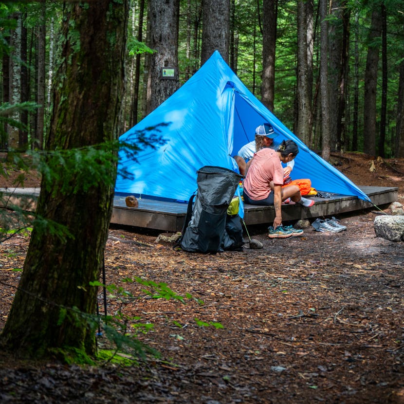 Two hikers rest in a Black Diamond Mega Light Tent after a day of hiking. 