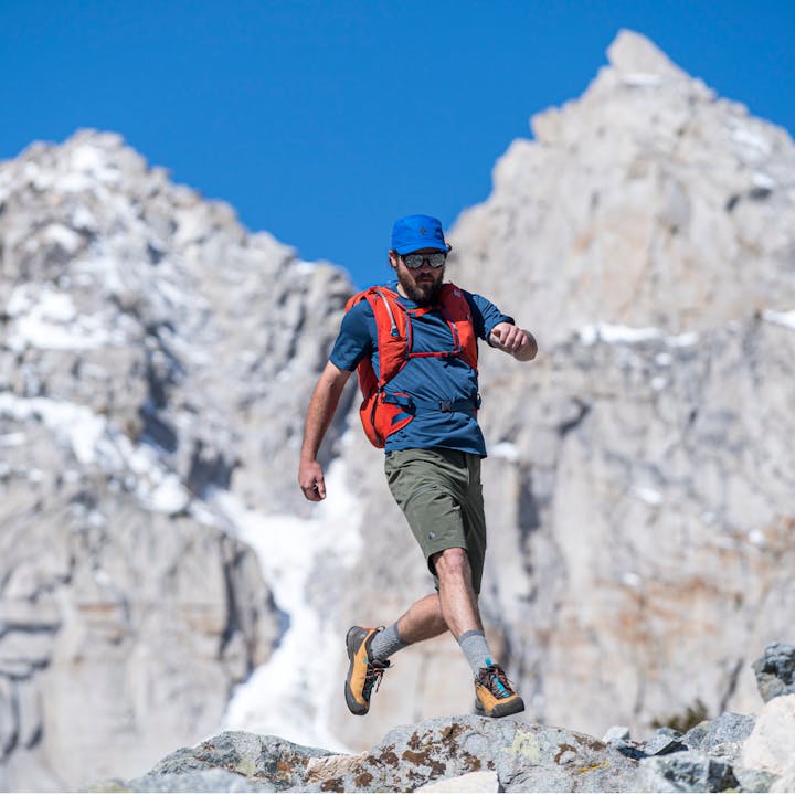 A Hiker leaps across some boulders in the wearing the Black Diamond Pursuit backpack and Mission footwear. 