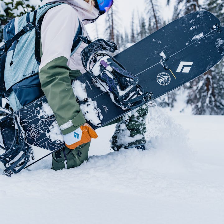 A splitboarder walks through thigh deep powder carrying her splitboard, scheming for the next life altering line. 
