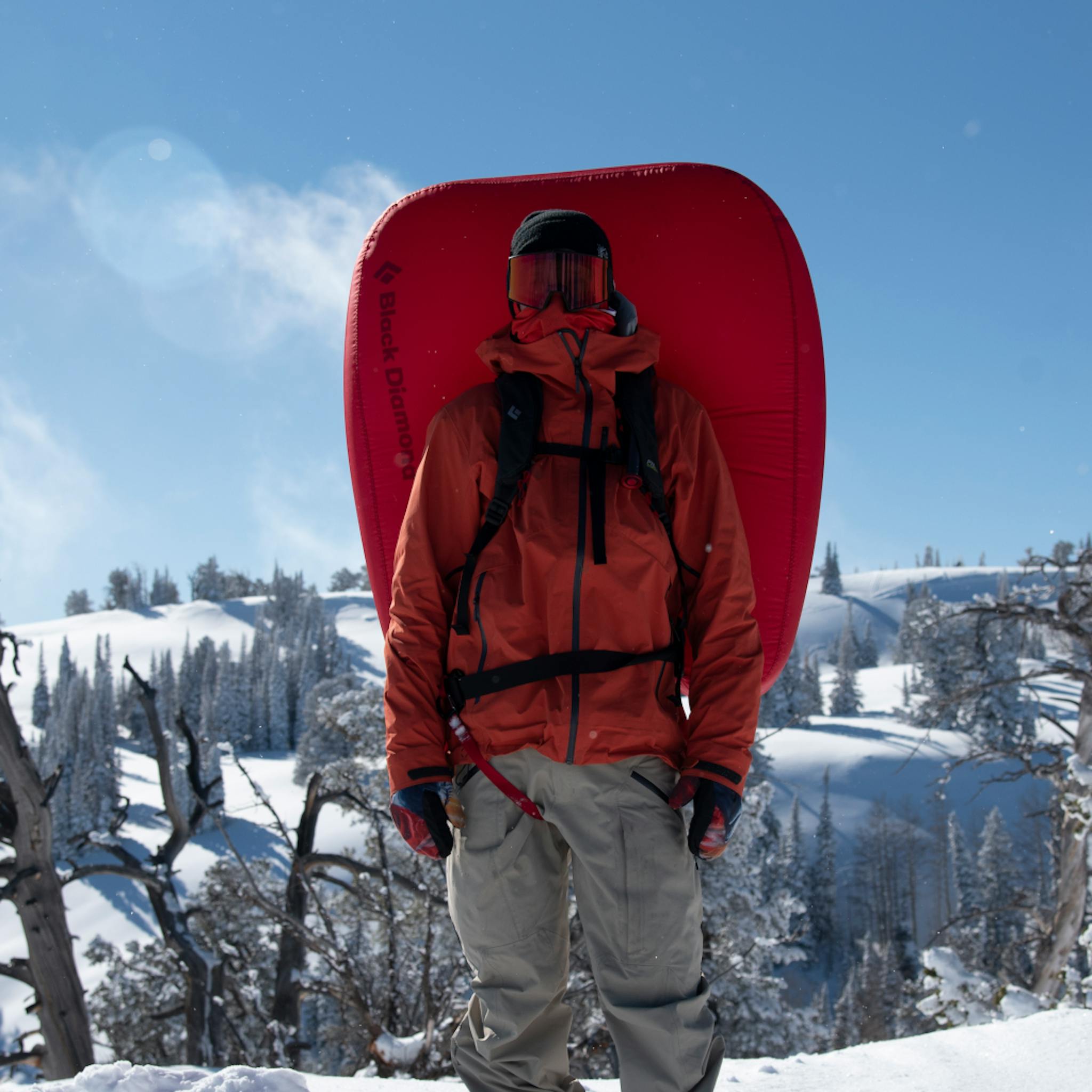 A snowboarder stands with a deployed Jetforce split pack.