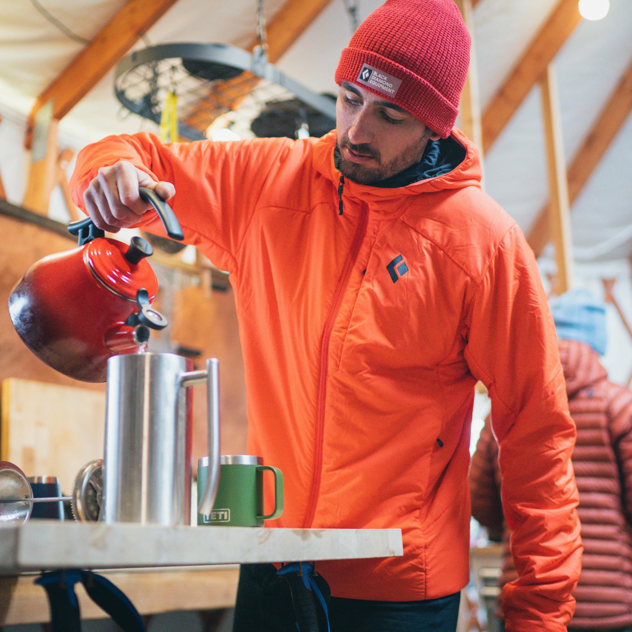 Un skieur de hors-piste préparant du café avant une patrouille à l'aube.