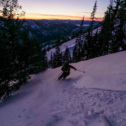 A backcountry skier descends as the sun rises. 