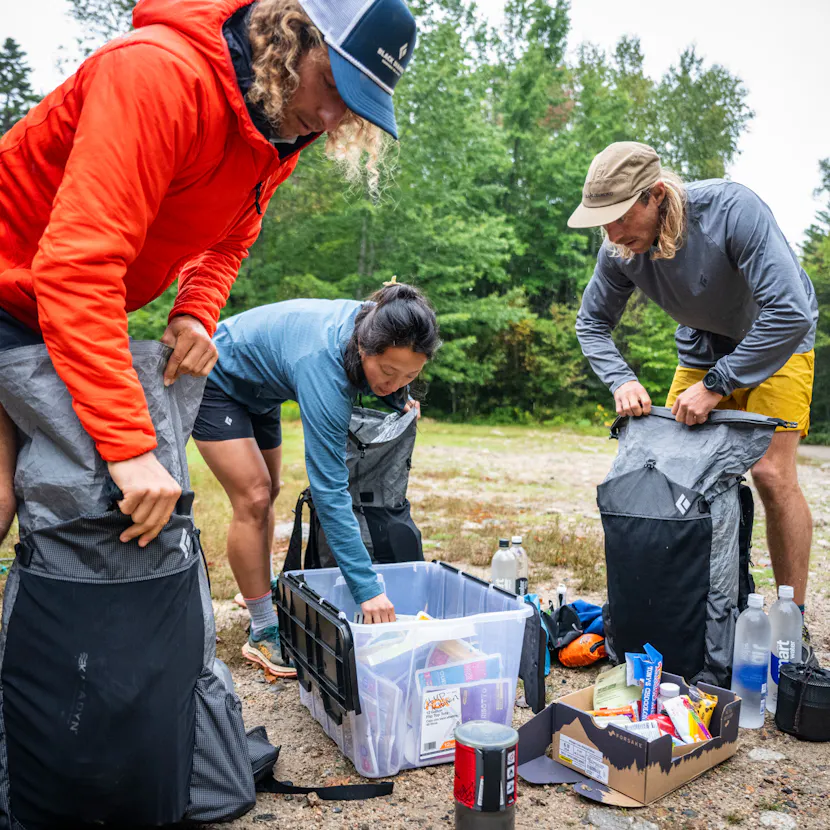 Three hikers sort food and equipment before a through hike.