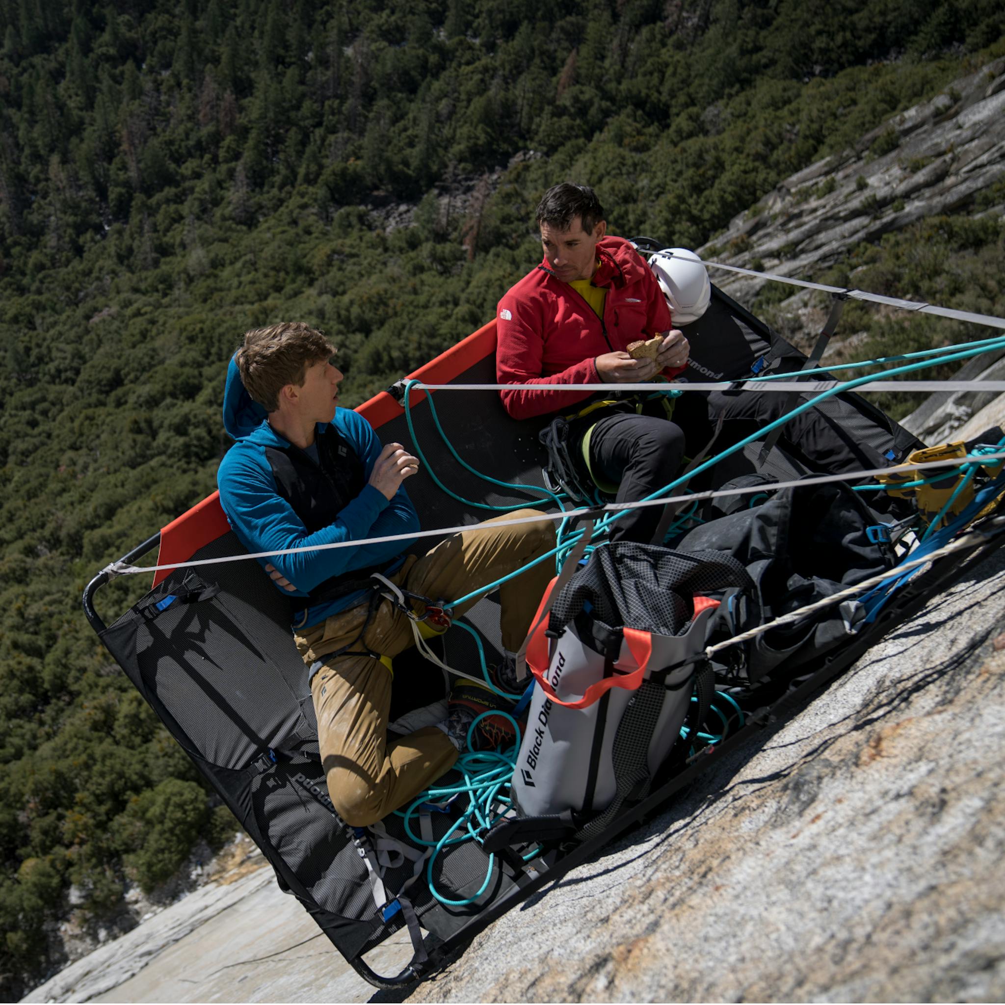 A climber wearing Black Diamond Coefficient LT hybrid hoody chills on a portaledge with Alex Honold.