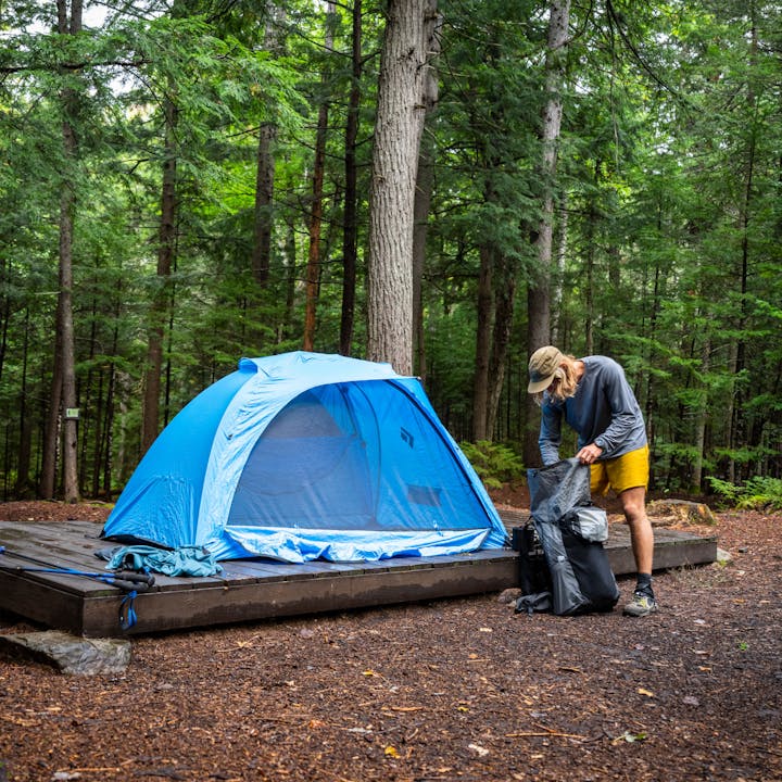 A hiker unpacks his Beta Light Pack next to his Black Diamond Hilight Tent. 
