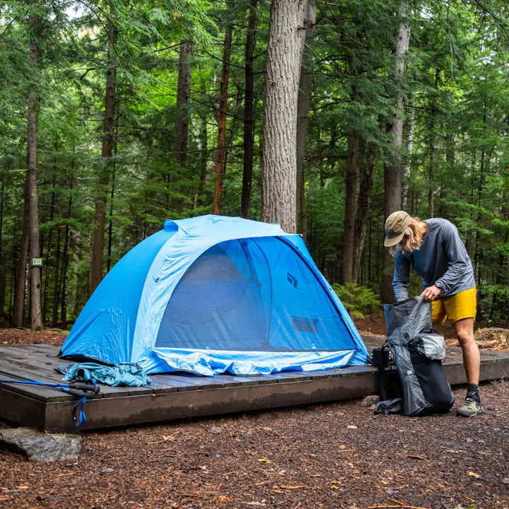 A hiker unpacks his Beta Light Pack next to his Black Diamond Hilight Tent. 