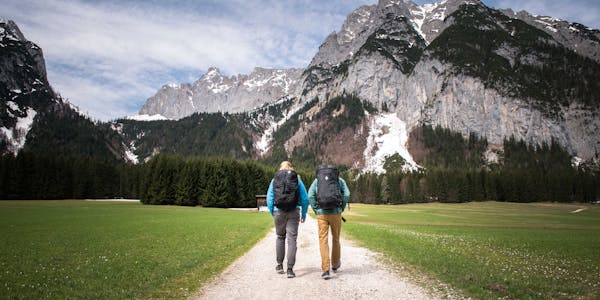 A photo by Andy Earl of two people walking in front of mountains 